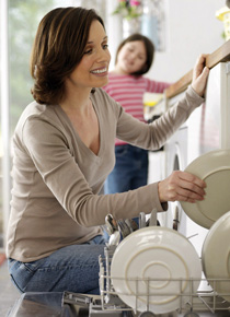 Frau räumt Geschirr in die Geschirrspülmaschine