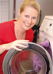 Frau füllt Wäsche in die Waschmaschine
